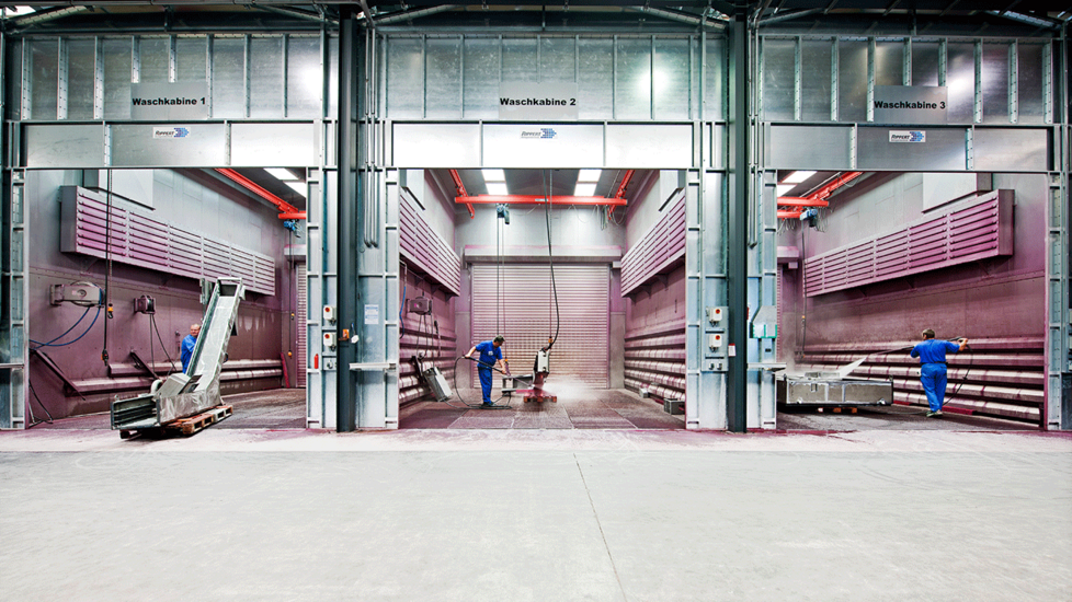 Mitarbeiter reinigen Maschinen in Waschkabinen - KNOLL Maschinenbau GmbH