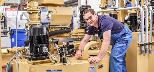 Mitarbeiter montiert Rückförderanlage mit Pumptechnik - KNOLL Maschinenbau GmbH